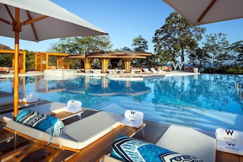 Relax by the serene pool surrounded by lush greenery and a picturesque view.