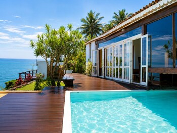 Un complexe hôtelier moderne doté d’une piscine, d’une terrasse en bois et offrant une vue sur l’océan.