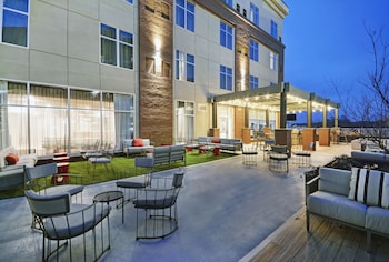 An outdoor patio area with a bar, seating, and a TV screen.