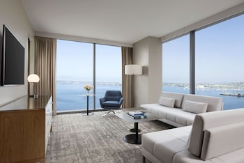 A modern restaurant with multiple dining areas, large windows offering ocean views, and contemporary lighting fixtures.