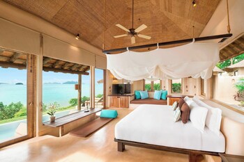 Relax by the serene infinity pool overlooking the calm sea and lush shoreline.