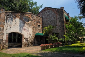 An open-air dining area with brick walls, arched ceilings, and multiple tables and chairs.