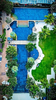 A resort pool area with multiple swimming pools, lounge chairs, and umbrellas.