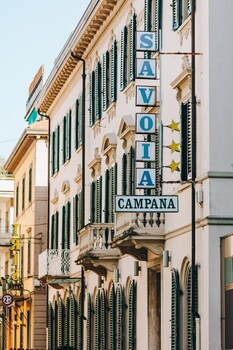 A street lined with historic buildings featuring green shutters and balconies.