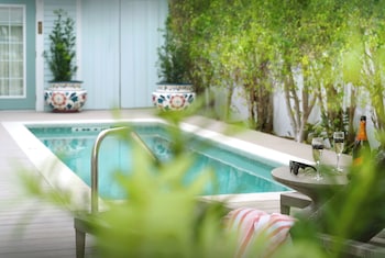 A two-story building with a white picket fence, palm trees, and a sign that reads 'DUVAL GARDENS.'
