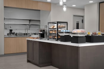En hotellinnergård med utomhusmöbler, en eldstad och en väl synlig skylt för Hilton Garden Inn.