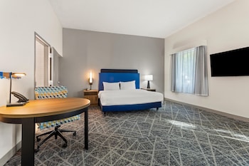 A modern interior with a blue sofa, yellow chairs, and a patterned rug.