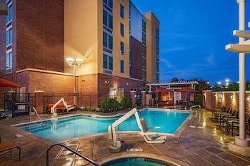 An outdoor patio with a brick wall, large windows, and outdoor seating including a sofa and chairs.