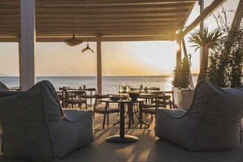 Enjoy al fresco dining with a view of the sea from this outdoor dining area, featuring comfortable seating and lush surroundings.