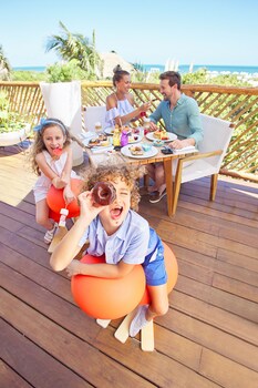 Une piscine aux eaux cristallines, entourée de palmiers et de chaises longues, avec un bâtiment moderne en arrière-plan.