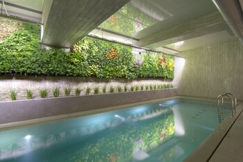 Une piscine intérieure offrant une vue dégagée sur le bassin, une échelle en métal et un mur recouvert de différentes plantes.