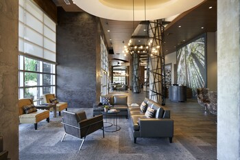 A spacious lobby with a modern design, featuring a mix of seating areas and a large window providing natural light.