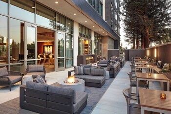 Un espacio al aire libre con sofás, mesas y un hogar para la chimenea.