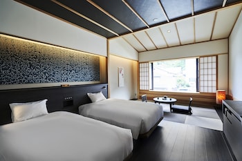 A traditional Japanese room with tatami flooring, wooden sliding doors, and a central decorative tree.