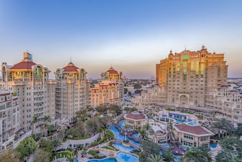 A high-rise hotel with multiple floors, large windows, and a rooftop terrace.