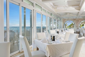 A resort with multiple swimming pools, a large building with multiple balconies, and a view of the ocean.