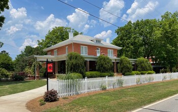 A two-story house with a wooden deck, a brick exterior, and a black metal staircase.