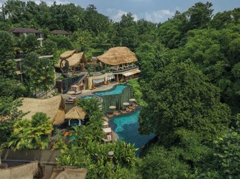 A resort with a pool, lounge areas, and thatched-roof structures.