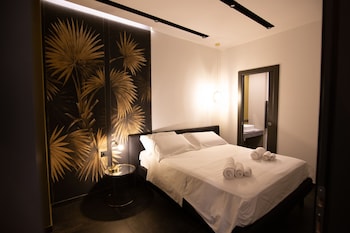 Une chambre d’hôtel moderne avec un grand lit, une table ronde et un mur orné de motifs de feuilles de palmier.
