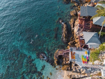 A coastal property with a view of the sea, featuring a wooden deck and a small boat dock.