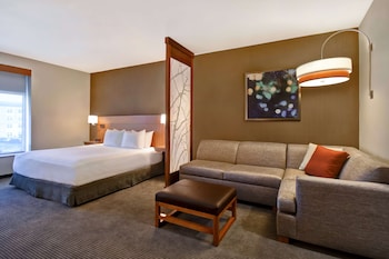 A modern hotel lobby with a self-service beverage station, seating area, and a television mounted on the wall.