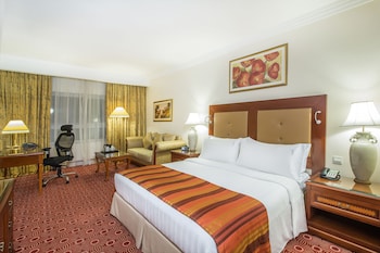 A spacious hotel lobby with multiple dining areas, a grand chandelier, and a modern glass facade.