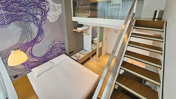 En modern hotellobby med en central pool, sittgrupper och utsikt över byggnadens fasad.