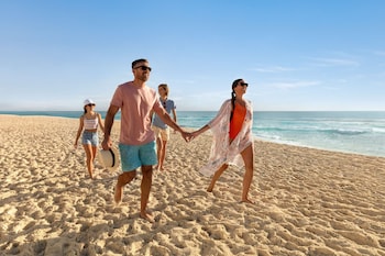 Exchange vows on a picturesque beachside lawn overlooking the ocean, surrounded by lush greenery and beautiful flowers.