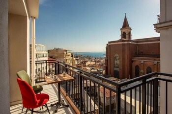 A balcony with a wooden table, two cups of coffee, and a small potted plant.