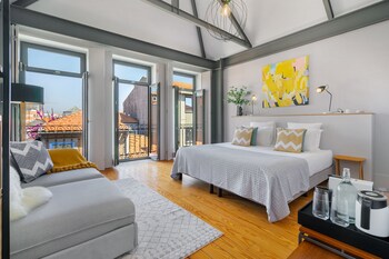 A modern bedroom with a large bed, a sofa, and a view of the city through large windows.