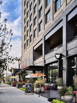 A spacious lounge area with a pool table, comfortable seating, a bar, and large windows offering views of the city.