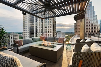 Eine Dachterrasse mit Feuerstelle, Sitzbereich und Blick auf die Skyline der Stadt.