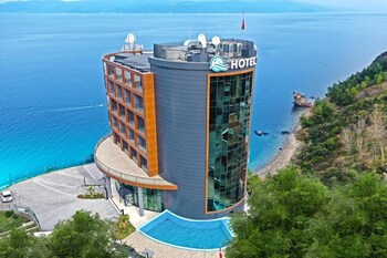 Un hotel moderno con zona de piscina, vistas al mar y un jardín paisajístico con flores amarillas.