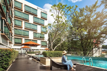 A woman sitting by a pool with lounge chairs and a waterfall in the background.