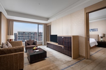 A spacious gym with various exercise equipment, large windows, and a modern ceiling design.