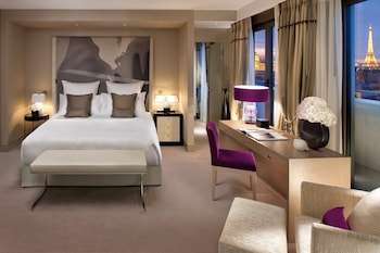 A hotel room with a bed, a desk, a mirror, and a bathroom with a shower.