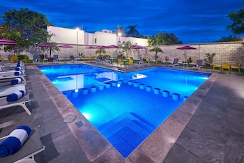 Una piscina al aire libre, sombrillas, sillones reclinables de piscina