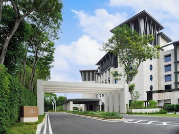 A hotel with a large pool, palm trees, and modern architecture.