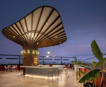 An outdoor bar area with a curved ceiling, bar stools, and tables.