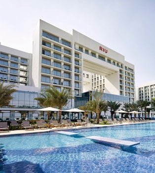 A resort with a large pool, beachside lounge chairs, and a view of the ocean.