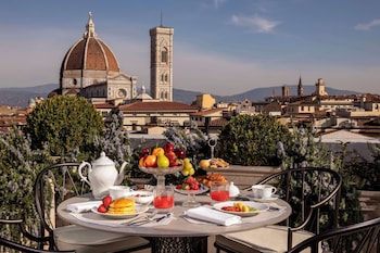 A table set with breakfast items and a view of historic buildings.