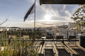 Relax on the rooftop terrace with city views, lounge chairs, and tables.