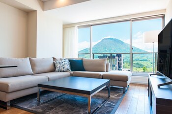 A modern living room with a large window offering a view of a snowy mountain landscape.