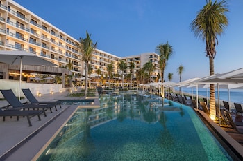A resort with multiple swimming pools, a beach, and a large building with balconies.