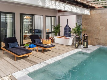 Ein Resort mit einer Steintreppe, die zu einem Poolbereich führt, umgeben von tropischen Pflanzen und Gebäuden im traditionellen Stil.