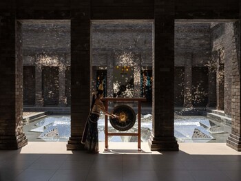 Un complexe hôtelier doté d’un escalier en pierre menant à un espace piscine, entouré de plantes tropicales et de bâtiments de style traditionnel.
