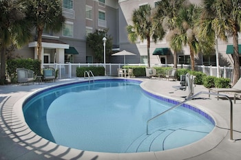 Relax by the fire pit surrounded by comfortable wicker chairs and lush palm trees.