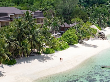 A beachfront hotel with multiple buildings, a pool area, and lush greenery.