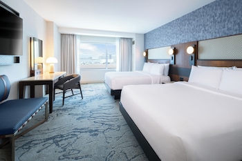 Un moderno vestíbulo de hotel con una escalera central, zonas de estar y una recepción.