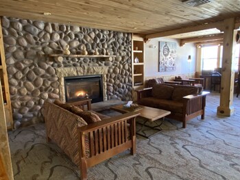 A spacious living area with a stone fireplace, wooden furniture, and a large sofa.
